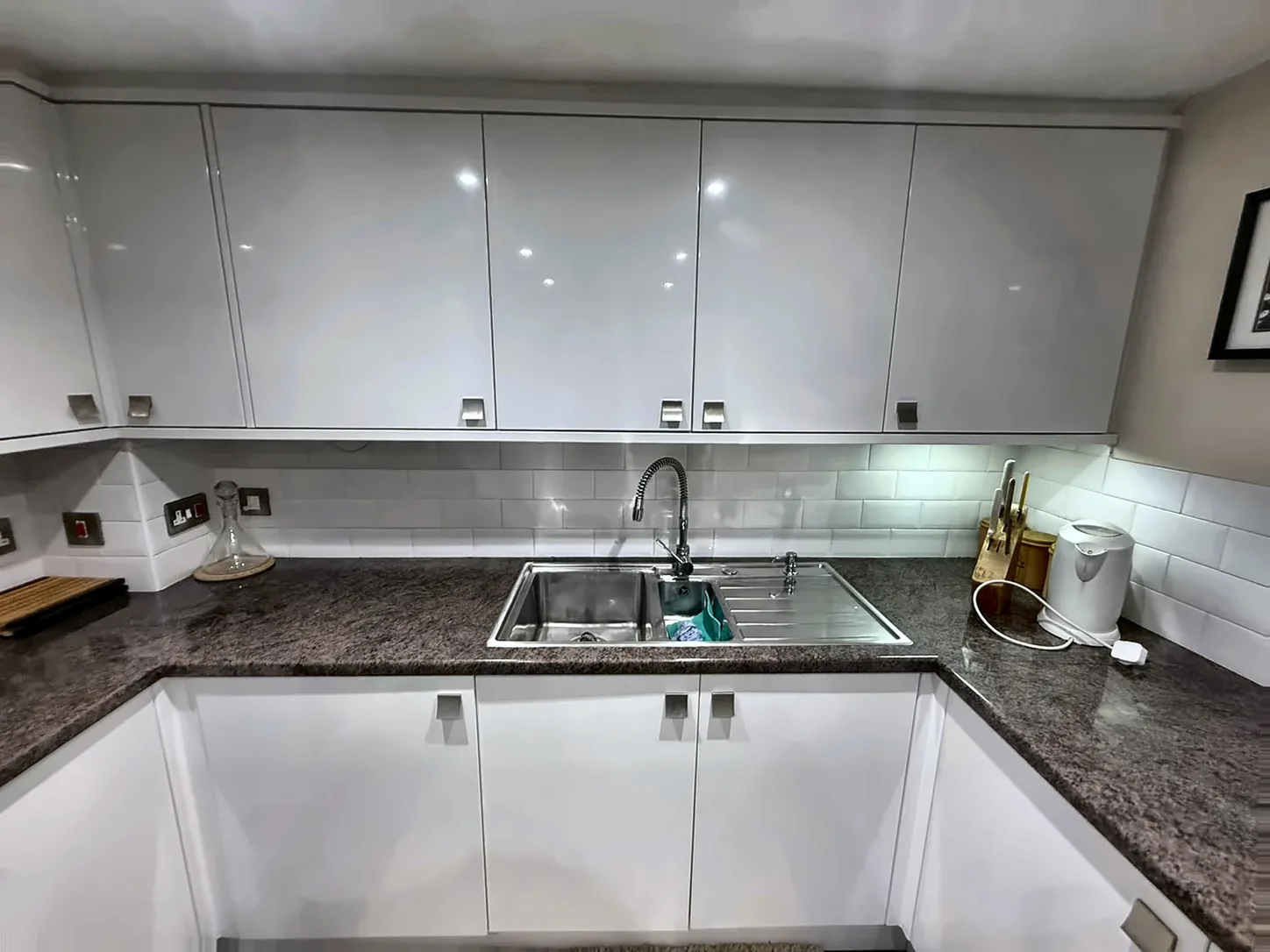 A white gloss kitchen with the worktop and sink left clean after an oven and appliance valet.